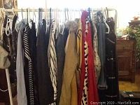 Photo showing variety of women's clothing hung on a rack including coats, jackets, dresses in multiple colors and patterns