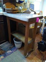 Full view of butcher block cart showing two wooden shelves and wheels below