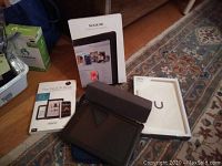 Nook Book tablet with protective cover, original box, and manual on a rug.