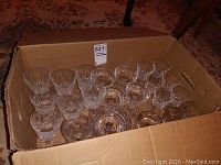 Box containing multiple stemmed glasses including water and wine glasses and footed dishes