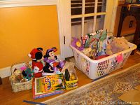 Overview of baskets and assortment of plush, coloring books, and toy containers on floor next to door