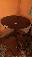 Full view of round wooden pedestal table with dark finish, showing surface and general shape