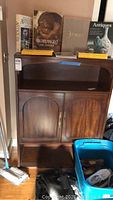 Wood cabinet with two doors and open top shelf, with items on top, showing overall look and condition.