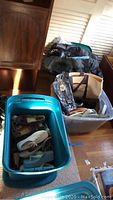Several pairs of women's shoes in a blue plastic storage bin, various styles and colors, some wear visible.