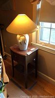 Photo of lamp and side table together next to a window illustrating the full set and size.