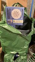 Green bag with visible box of 6 inch clear lighted sphere, blue box with sphere image