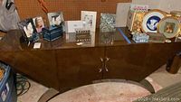 Full front view of large rectangular console table with glossy brown finish, curved silver handles and storage doors, showing surface and shape.