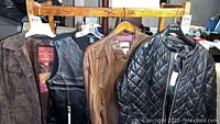 Four leather and suede outerwear garments on hangers, visible tags on some.