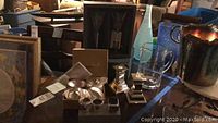 Wide view showing Waterford crystal flutes in box, pitcher, candlestick holder, and silver-tone containers arranged on table.