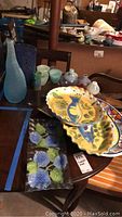 Photo of hand painted platters, rectangular floral glass platters, and glass vases on wooden table