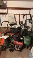 Photo shows overall lot items including two Scotts seed spreaders green, Stinger wet/dry vacuum cleaner red/black, Ridgid 16 gallon wet/dry vacuum, Remington electric tiller orange, dolly metal with rust, Toro collection bag green, extension cord