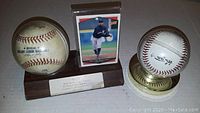 Photo showing two baseballs. One baseball mounted on wooden plaque with text plate. The other baseball with 'Sweet Spot' inscription mounted on a clear holder. Also shows a baseball card in protective sleeve.