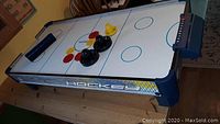 Full view of the Harvill air hockey table with pucks and pushers on the playing surface.