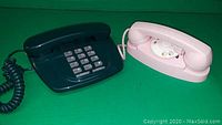 Photo of two corded telephones; one black with push buttons and one light pink with rotary dial