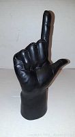 Black hand statue viewed front side, showing index finger up and thumb extended forming an 'L' shape.