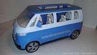 Blue and white Barbie Volkswagen bus toy side view showing seats and windows.