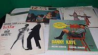 Photo showing four vinyl record album covers including Danny Kaye, 12 Top Hits, Lester Lanin, and King of Jazz records.