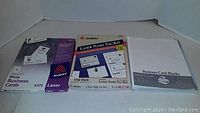 Photo showing three Avery brand products: a pack of white laser business cards (5371), a laser name tag kit, and a pack of white business card blanks.