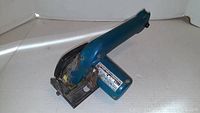Side angle view of Makita cordless hand saw showing blue housing and wear marks.