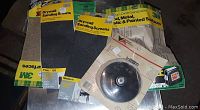 Photo showing 3M branded drywall sanding sheets and screens of various grits alongside a package containing a round polishing or grinding wheel attachment.