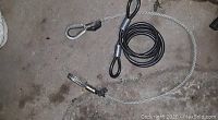 Two wire lock cords on the floor, one steel cable with metal clips and one black coiled cable