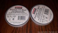 Two rolls of black Plymouth Premium 111 vinyl electrical tape on a wooden surface.