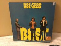 Front cover of the Bee Gees 'Best' double LP showing band members and album title in yellow text on blue background with visible corner tear and edge wear.