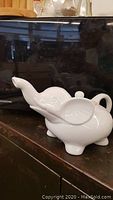 Side view showing elephant trunk-shaped spout and elephant body design of the teapot.