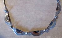 Close-up of front side showing five fancy half-circle links with brass and oxidized silver accents.