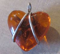 Close-up photo of the vintage amber heart pendant showing amber clarity, natural inclusions, and thick sterling silver wire wrapping tight against the stone.