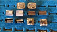 Front view of five pairs of silver tone vintage cuff links on a blue textured background, showing different geometric designs.