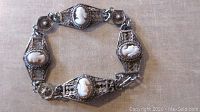 Full view of the vintage silver filigree bracelet with four shell cameos, laid out flat.