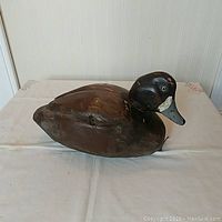 Front-left angled view showing the wooden duck decoy with carved and painted details.