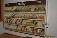 Front view of wall-mounted display case labeled ‘anchor’ with multiple clear bins containing various fishing lures.