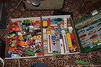 Two trays filled with assorted Majorette die-cast toy vehicles including cars, trucks, and construction vehicles