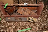 Wooden tool box filled with vintage wooden hand planes and a clamp.