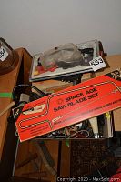 Overhead view of tray containing clear safety goggles, Space Age saw blade set box and mixed tools