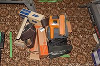 Photo of multiple sanding belts, Black & Decker handheld sander, and other original packaging laid on carpet