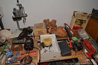 Wide view of table with drills, stand, lamp, tool belt, vise and other accessories