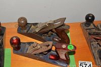 Two metal hand planers placed on wooden table, showing wooden knobs and dark metal bodies.