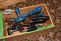 Top-down view of wooden box containing two blue hand drills, a wooden brace, drill bits, and other tools.