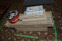 Stacked boxes of router attachments and tin of shoelaces on patterned rug