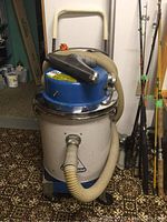 Full view of Dustbane shop vacuum unit on cart with attached vacuum hose and handle.
