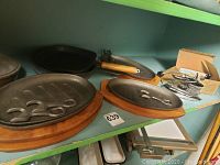 Overview of cast iron cookware and wooden trivets showing frying pans, a grill pan, and a can opener.
