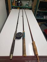 Three fly fishing rods laid side by side on white table