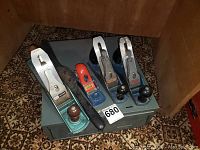 Four hand planes on top of a gray two-drawer metal toolbox