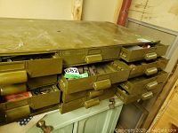 Photo of metal cabinet with six drawers open showing contents including files, chisels, bolts and nuts.
