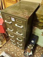 Front view of the green metal filing cabinet showing all five drawers and surface wear.