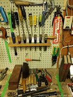 Full view of tools on pegboard and workbench including chisels, screwdrivers, brush, and other tools.