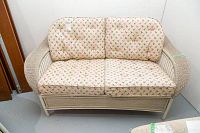 Front view of beige loveseat with floral cushioned seat and backrest.